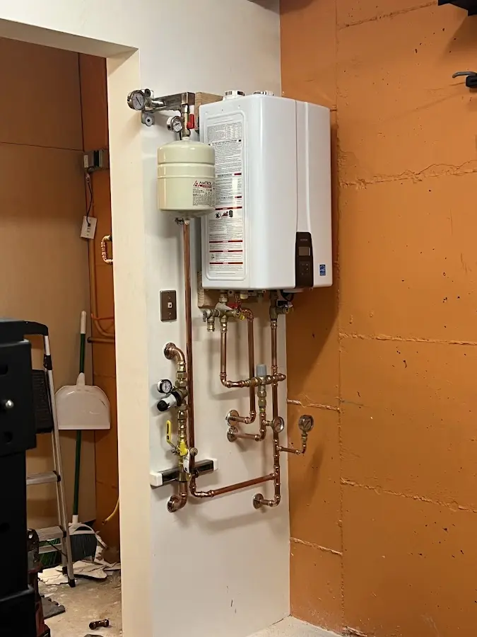 Plumbing technician inspecting water heater connections in Greensburg